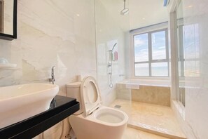 Une salle de bain avec des toilettes, un lavabo et une douche.