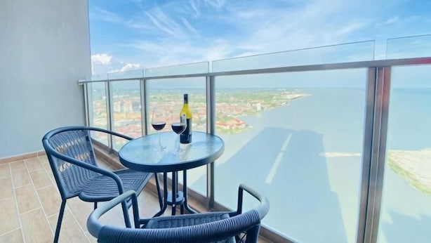 Ein Balkon mit Tisch, Stühlen, einer Weinflasche und einem Weinglas.