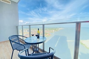 A balcony with a table and chairs, a bottle, and a glass of wine.