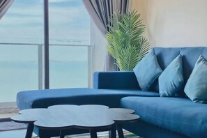 Un canapé bleu, une table basse ronde et une grande plante en pot dans une pièce offrant une belle vue.
