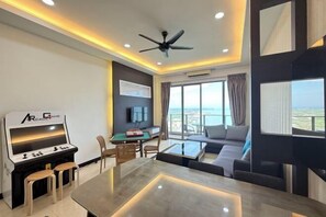 A modern living room with a gaming console, a sofa, a dining table, and a large window with a view.