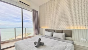 Ein Schlafzimmer mit einem großen Bett, einem Kopfteil, einem Nachttisch und Blick auf das Meer.