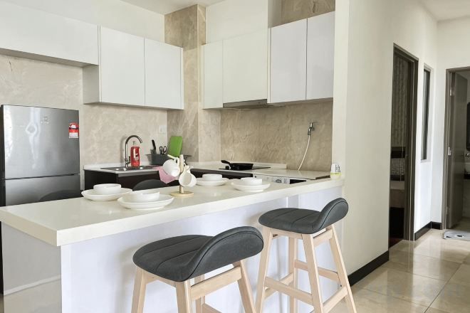A modern kitchen with a central island, bar stools, and a refrigerator.