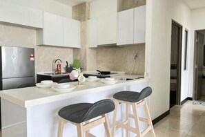 Eine moderne Küche mit einer zentralen Kochinsel, Barhocker und einem Kühlschrank.