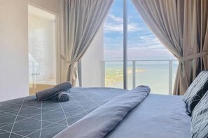 Ein Hotelzimmer mit Bett, Vorhängen und Meerblick.