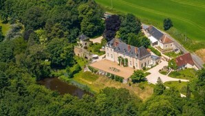 An aerial view of a large estate with multiple buildings, a pond, and surrounding greenery. - Huberdière Castle (Nazelles-Negron)