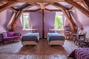 A bedroom with two beds, a purple sofa, and a wooden ceiling. - Huberdière Castle (Nazelles-Negron)
