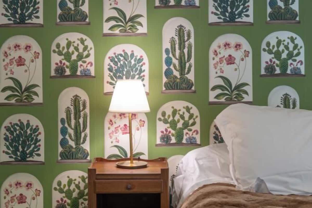A bedroom with a green wall, a bed with white bedding, and a nightstand with a lamp.