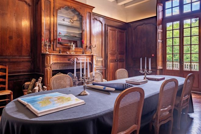 A dining room with a table set for six, surrounded by wooden chairs.