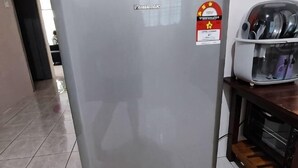 A kitchen area with a refrigerator, a microwave, and a toaster on the counter.