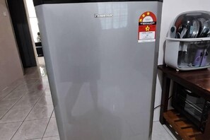A kitchen area with a refrigerator, a microwave, and a toaster on the counter. - TAWAU COZY HOMESTAY @ MEGAH JAYA 10 (Tawau)