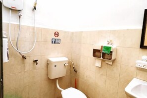 A small bathroom with a toilet, a sink, and a shower.