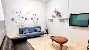 A living room with a sofa, a coffee table, a TV, and a decorative wall. - TAWAU COZY HOMESTAY @ MEGAH JAYA 10 (Tawau)