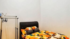 A single bed with a patterned bedspread, a bedside table, and a wall-mounted air conditioner.