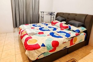 Un lit recouvert d’une couverture aux couleurs vives, un canapé sombre et une petite table avec une lampe.