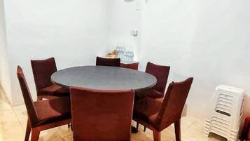 A round table with six chairs, a small table with a lamp, and a white wall.