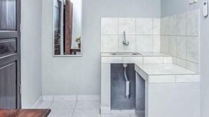 A modern kitchen with a built-in sink, a mirror, and a wooden table. - Amor Homestay near Eltari International Airport Mitra RedDoorz (Liliba)