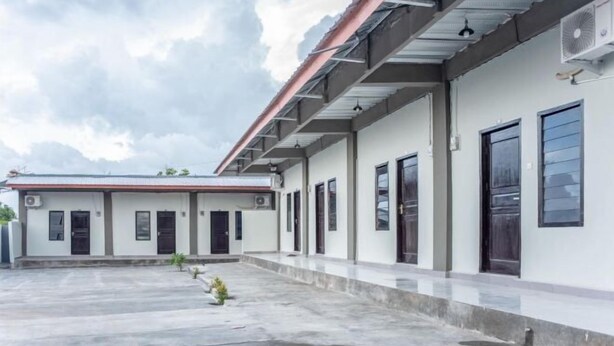 A building with a flat roof, multiple doors, and a concrete courtyard. - Amor Homestay near Eltari International Airport Mitra RedDoorz (Liliba)
