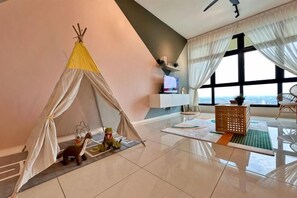 Een kamer met een tent, een televisie, een bank en uitzicht op zee.