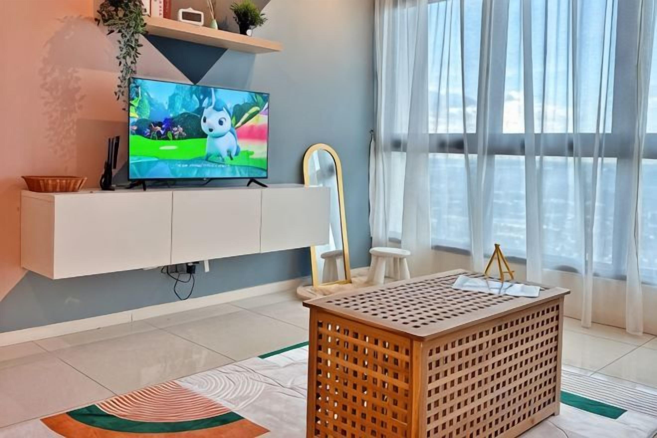 A modern living room with a flat-screen TV, white entertainment unit, and a wooden coffee table.