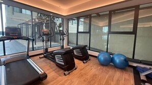 Et fitnessrum med løbebånd, crosstrainere og træningsbolde.