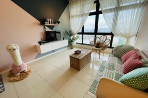 Een moderne woonkamer met een bank, een salontafel, een televisie en een raam met gordijnen.