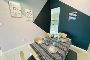 A dining area with a table set for six, chairs, framed artwork on the wall, and a black accent wall. - Paradigm Mall Residence L30 By Ucome Homestay (Tebrau)