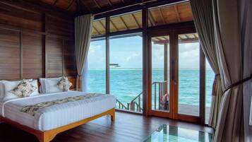 Ein Schlafzimmer mit einem hölzernen Bett, großen Fenstern und Meerblick.