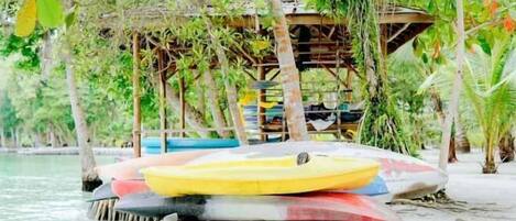 A beach with a wooden structure, a yellow and red kayak, and a blue boat.