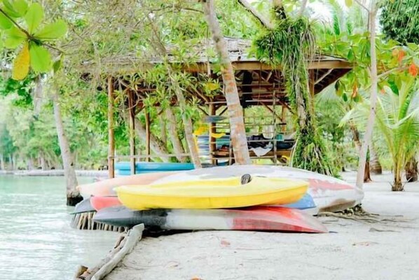 Una spiaggia con una struttura in legno, un kayak giallo e rosso e una barca blu.