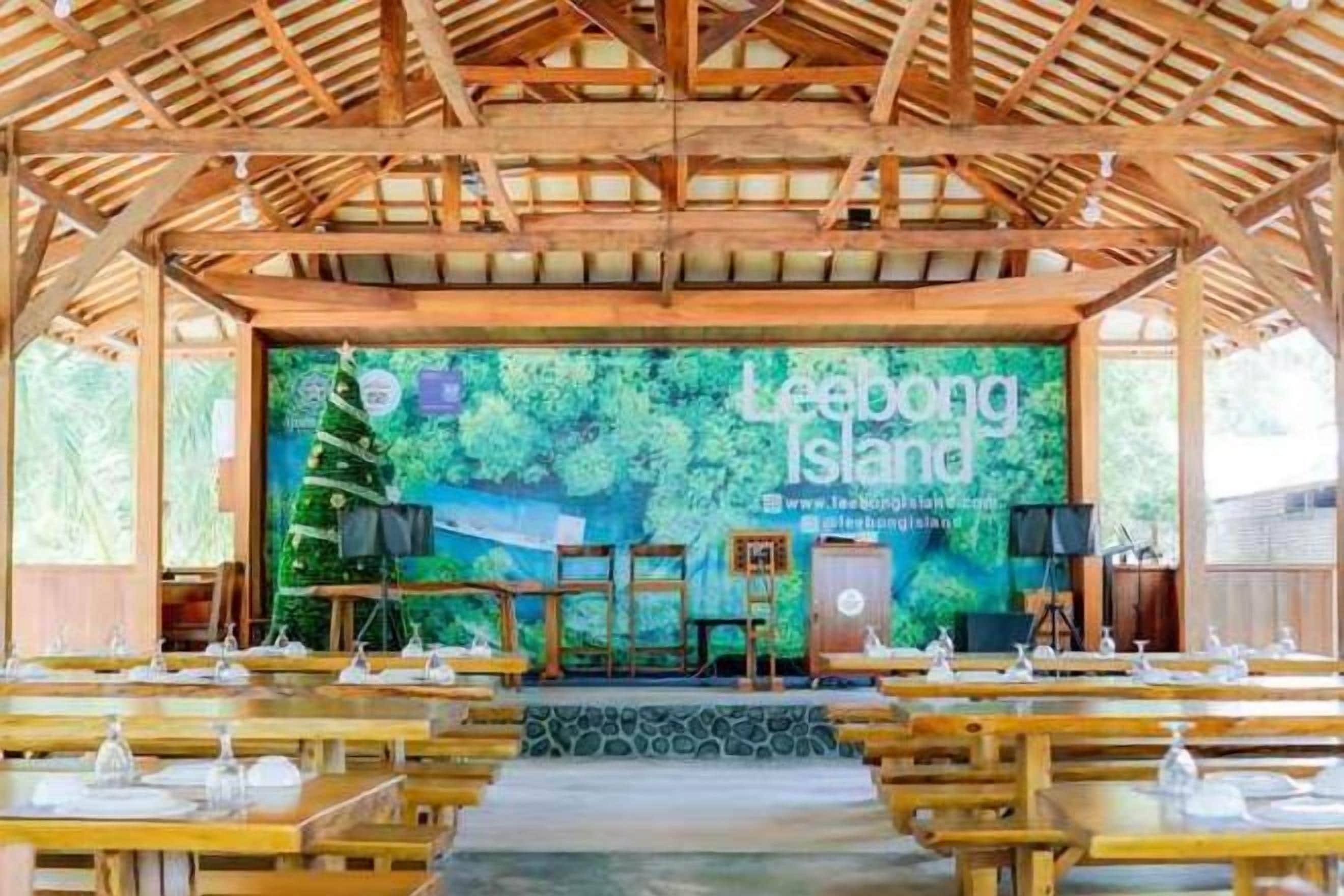 A covered outdoor dining area with a stage in the background, tables set with white tableware, and a banner reading 'Leebong Island.'