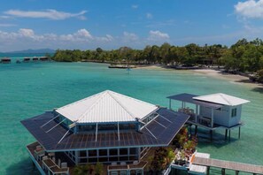 A resort with overwater bungalows, clear turquoise water, and a forested island in the background. - Leebong Island (Pegantungan)