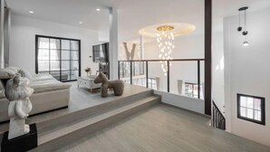 A modern interior with a staircase leading to a balcony, a sofa, a decorative horse sculpture, and a chandelier. - Luxury Private Pool Villa "Psalms 23 Residence @Huaikwang" (Bangkok)