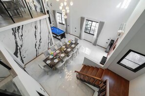 A dining area with a marble wall, a long table, and a blue pool table. - Luxury Private Pool Villa "Psalms 23 Residence @Huaikwang" (Bangkok)