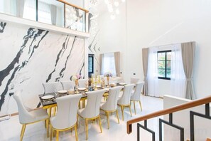 A dining area with a marble wall, a dining table set with chairs, and a staircase leading to an upper level. - Luxury Private Pool Villa "Psalms 23 Residence @Huaikwang" (Bangkok)