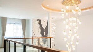 A modern hotel lobby with a glass railing, a marble wall with a geometric design, and a hanging light fixture. - Luxury Private Pool Villa "Psalms 23 Residence @Huaikwang" (Bangkok)