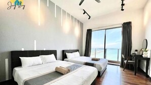 A hotel room with two beds, a desk, a chair, and a large window with a view of the sea. - SilverScape Melaka/ 3BR/ 6-10 pax/Bathtub/Seaview/ Infinity Pool/ Jonker St (Melaka)