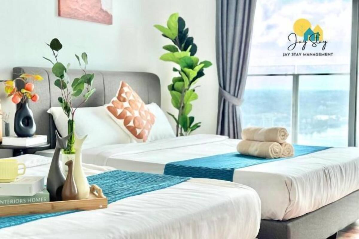 Een hotelkamer met twee bedden, uitzicht op de stad, een raam met gordijnen en een logo op het raam.