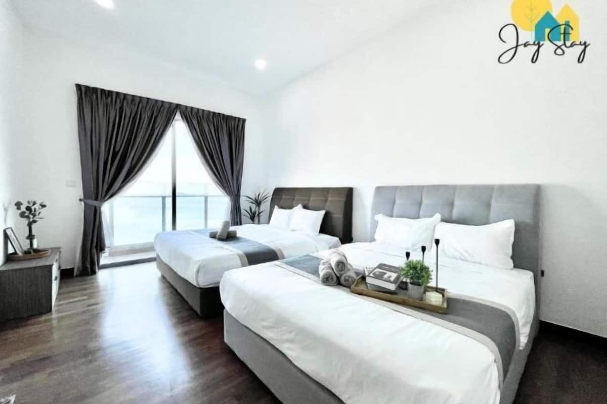 Een moderne hotelkamer met twee bedden, een groot raam met gordijnen en uitzicht op zee.