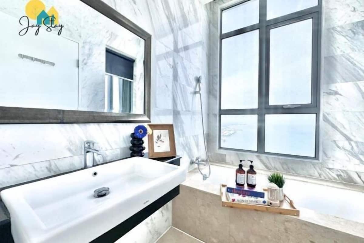 Een badkamer met een wit wastafelmeubel, een spiegel, een douche en een raam.