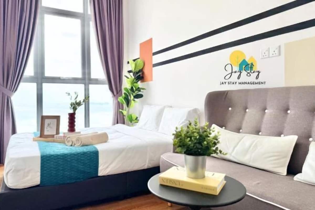 Een moderne hotelkamer met een bed, een bank, een bijzettafeltje en uitzicht op zee.
