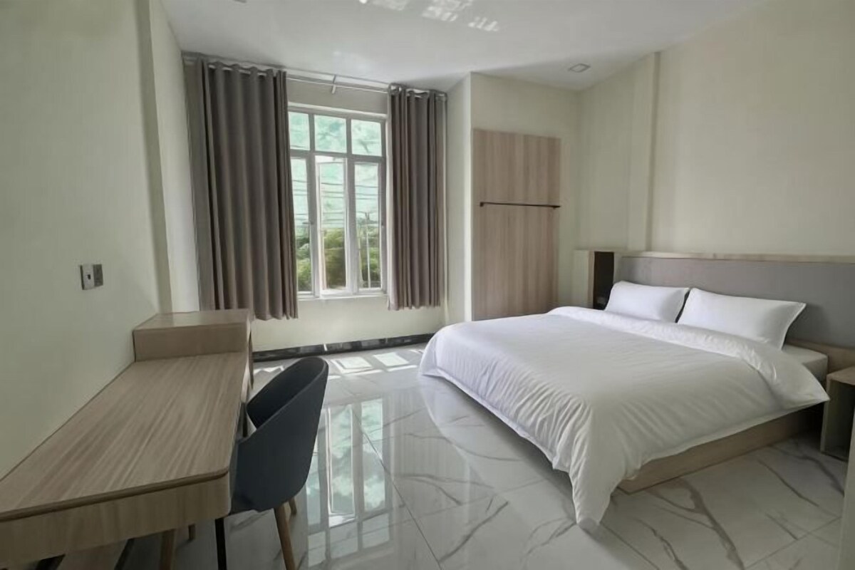 A hotel room with a bed, a desk, and a chair.