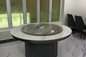 Ein runder Tisch mit Glasplatte und einigen Stühlen darum.