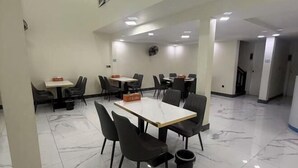 A hotel dining area with tables and chairs, a trash bin, and a ceiling fan. - zhuo' bo hotel (Ta Khmau)