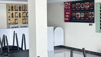 Un hall d’hôtel avec un comptoir de réception, un menu affiché au mur et une étagère remplie de bouteilles.