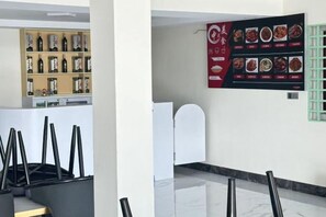 Un hall d’hôtel avec un comptoir de réception, un menu affiché au mur et une étagère remplie de bouteilles.