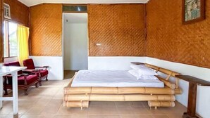 A room with a large bed, a desk, and two red chairs.