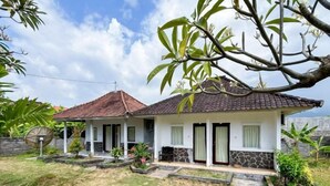 A single-story house with a tiled roof, a front porch, and a small garden area. - Hepi Bungalow Lovina Mitra RedDoorz (Bali)