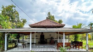 A covered outdoor area with a tiled floor, a table and chairs, and a small water feature. - Hepi Bungalow Lovina Mitra RedDoorz (Bali)