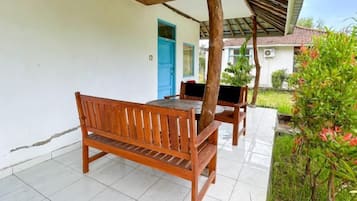 A wooden bench and table under a pergola on a tiled patio.